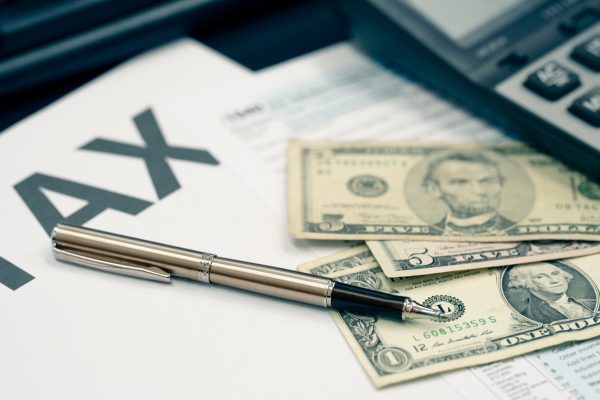 Tax season concept. Tax planning and consulting service business. Pen, calculator, dollar banknote, and income tax return form for filling and calculating tax payments. Money and financial concept.